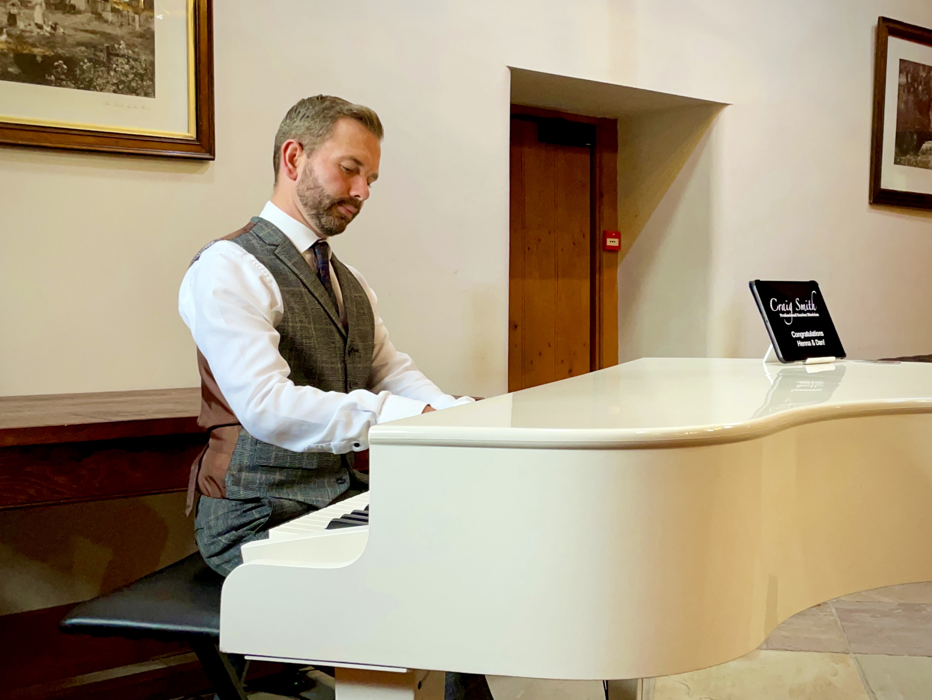 Wedding pianist Craig Smith playing his white piano during a Browsholme Hall wedding reception