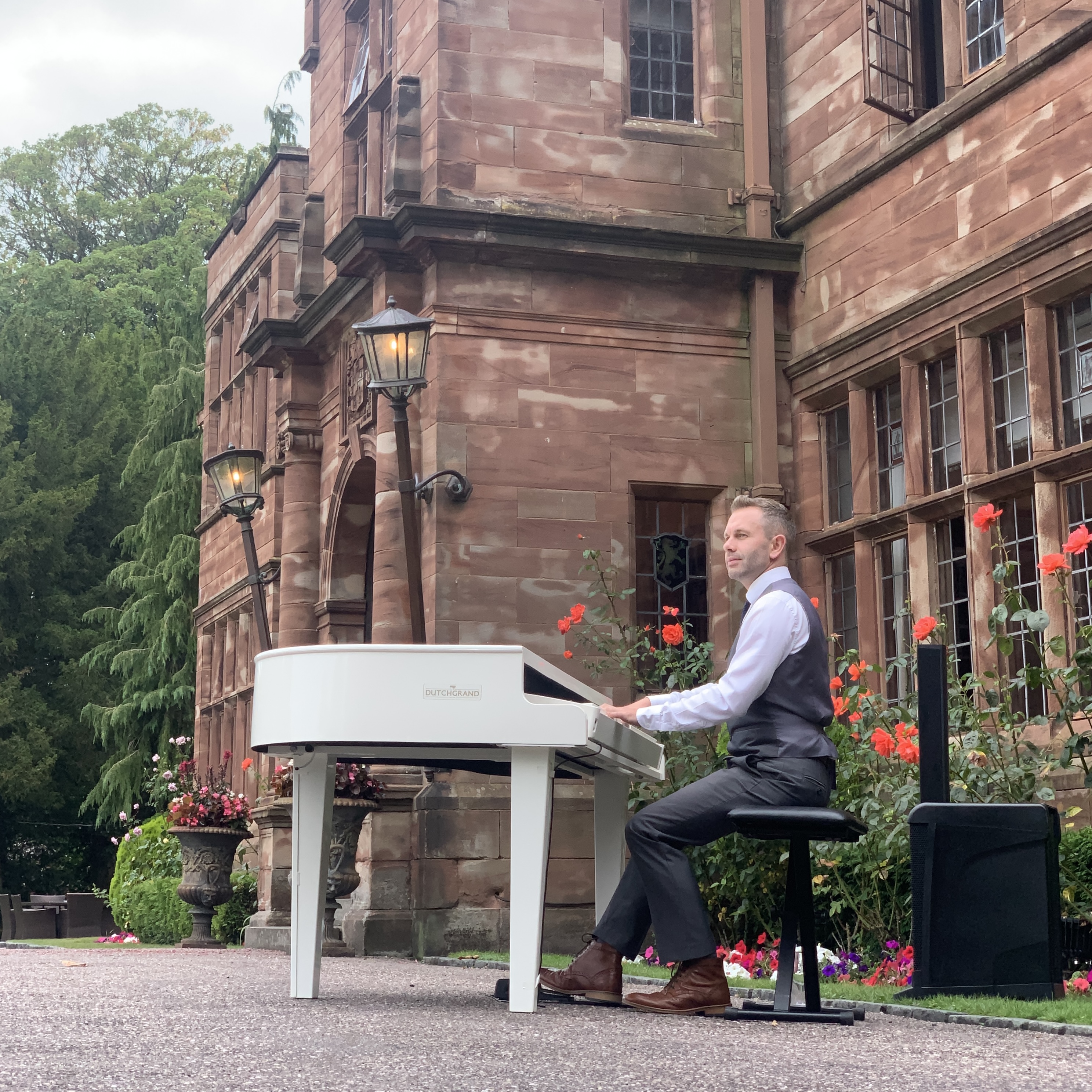 Wrenbury Hall pianist Craig Smith plays a white baby grand piano ouside the venue